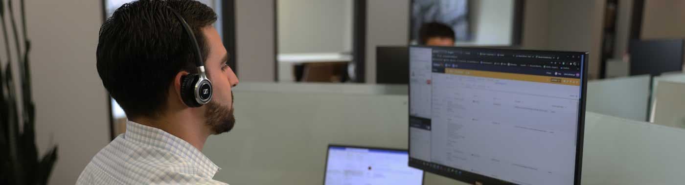 A man wearing a headset is sitting in front of a computer.